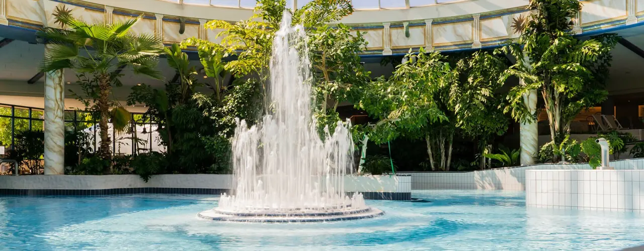 Grosszügiger Innenpool mit Springbrunnen und tropischen Pflanzen im Vital Hotel Frankfurt