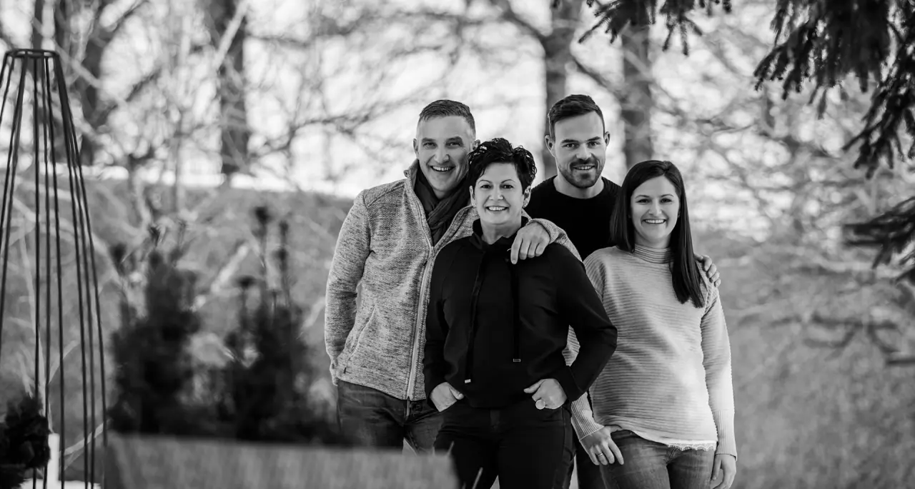 Schwarz-Weiss Gruppenfoto von vier lächelnden Personen im Aussenbereich des Landhotel Brandlhof.