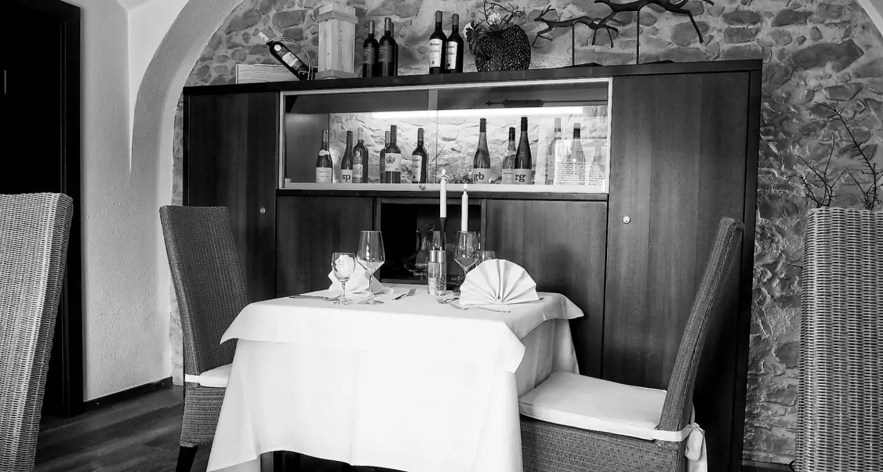 Gedeckter Tisch für zwei Personen mit Kerzen und Weinflaschen im Restaurant des Landhotel Brandlhof.