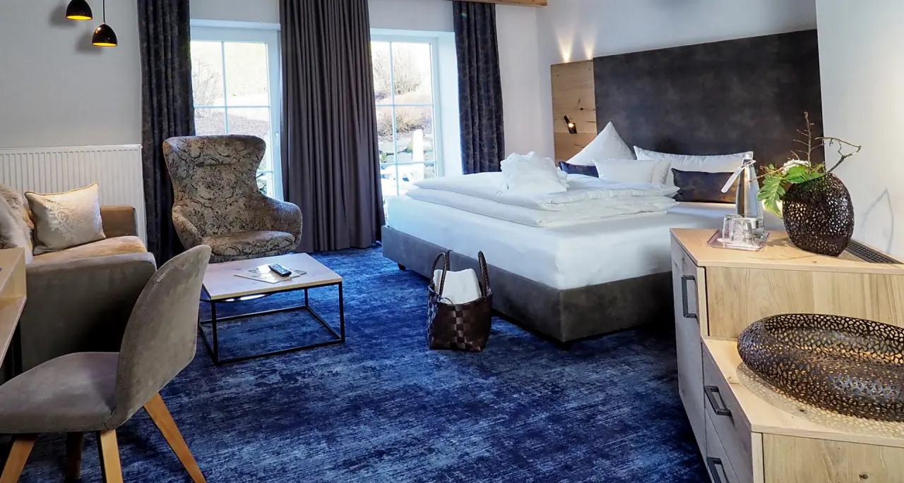 Gemütliches Hotelzimmer mit Doppelbett, Sitzbereich und Blick ins Grüne im Landhotel Brandlhof.