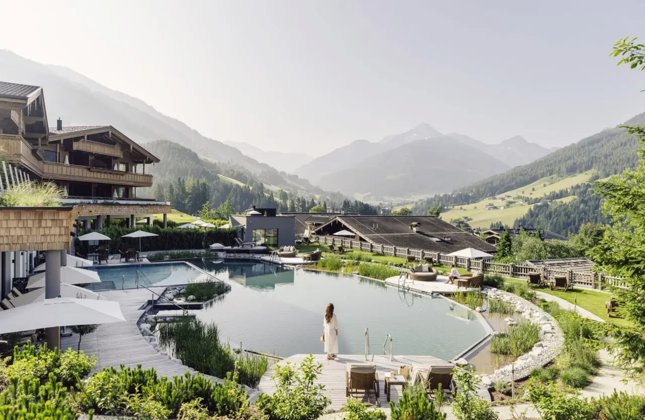 Der Böglerhof: Grosszügiger Naturbadeteich und Poolbereich mit Alpenpanorama, umgeben von grüner Natur.