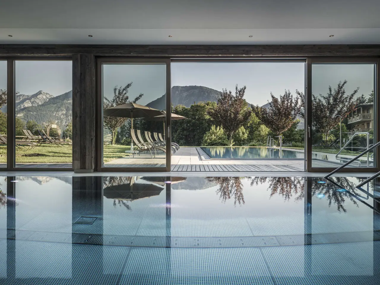 Grosszügiger Innen- und Aussenpool mit Bergblick im Wellnessbereich des Hotel Bachmanngut.