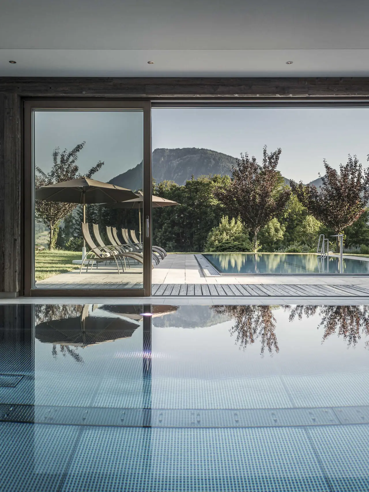 Innen- und Aussenpool mit Bergblick im Wellnessbereich des Bachmanngut Hotels. Entspannung am Pool mit Naturpanorama.