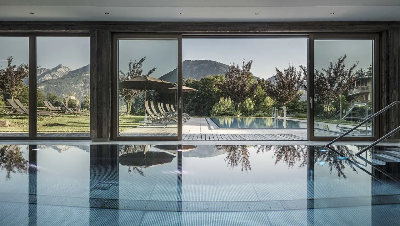 Innen- und Aussenpool des Bachmanngut Hotels mit Bergblick. Entspannung pur im Wellnessbereich.