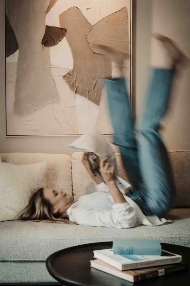 Gast entspannt lesend auf einem Sofa im Hotelzimmer des Sonnhof Alpendorf.