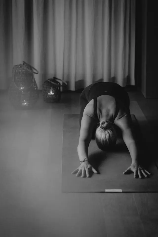 Entspannende Yoga-Session im Wellnessbereich des Sonnhof Alpendorf. Eine Frau in Kindeshaltung auf der Yogamatte.