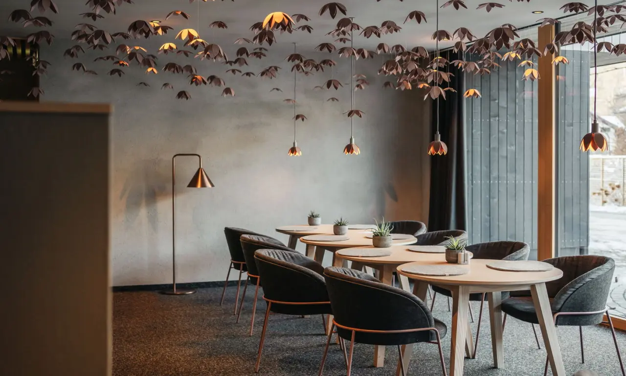 Modernes Restaurant der Amrai Suites mit stilvollen Tischen, Stühlen und einzigartiger Deckenbeleuchtung.