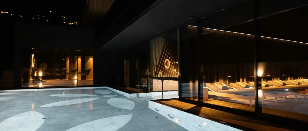 Abendliche Wellness-Oase mit Ruheliegen und beleuchtetem Wasserbecken im Amrai Suites.