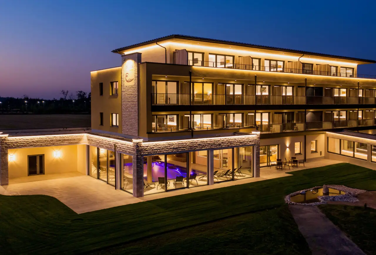 Beleuchtete Aussenansicht des Hotel Gasthof Enichlmayr bei Nacht mit sichtbarem Innenpool und Gartenbereich.