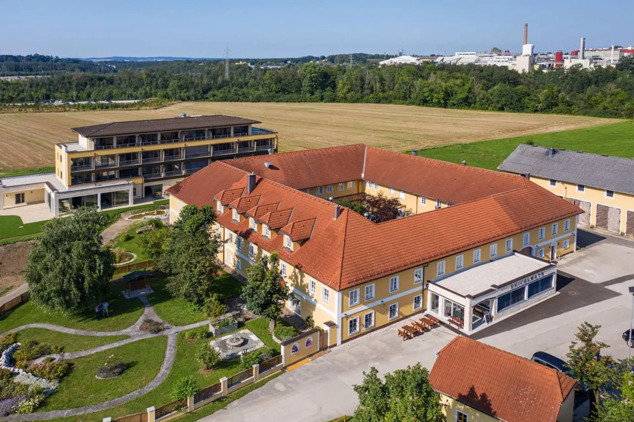 Luftaufnahme des Hotel Gasthof Enichlmayr mit traditionellen Gebäuden, modernem Anbau und Gartenanlage umgeben von Feldern.