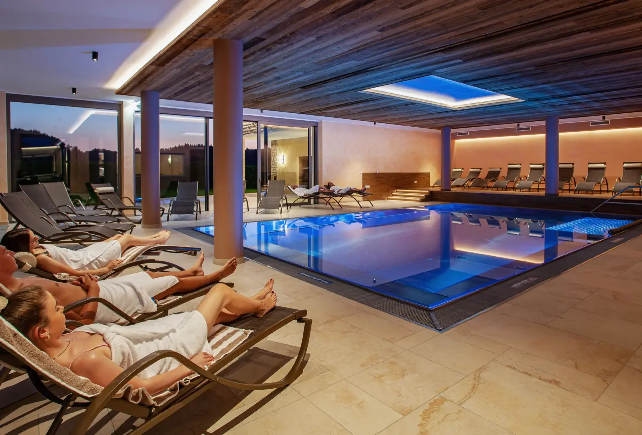 Entspannender Innenpoolbereich mit Liegen und Blick ins Grüne im Hotel Gasthof Enichlmayr.