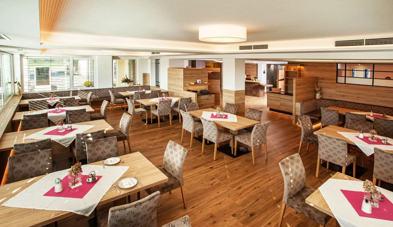 Helles, modernes Restaurant im Hotel Gasthof Enichlmayr mit Holzböden, gemütlichen Tischen und roten Akzenten.