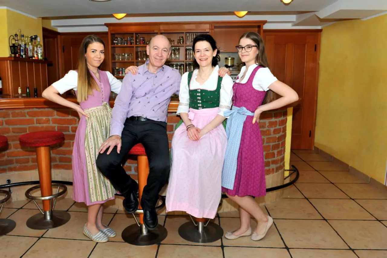 Hotel Gasthof Enichlmayr Familie in Tracht an der traditionellen Hotelbar.