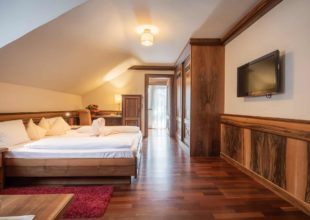 Gemütliches Doppelzimmer im Dachgeschoss des Alpenpark Resort mit Holzelementen, Doppelbett und TV.