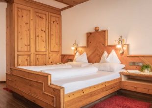 Gemütliches Doppelzimmer mit hellem Holzmobiliar und bequemen Betten im Alpenpark Resort.