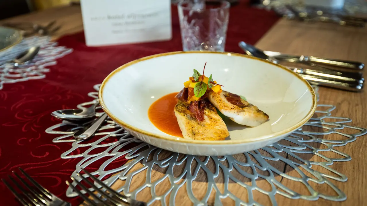 Fein angerichtetes Fischgericht mit Sauce und Gemüse auf einem Teller im Restaurant des Hotel Alpenrose.