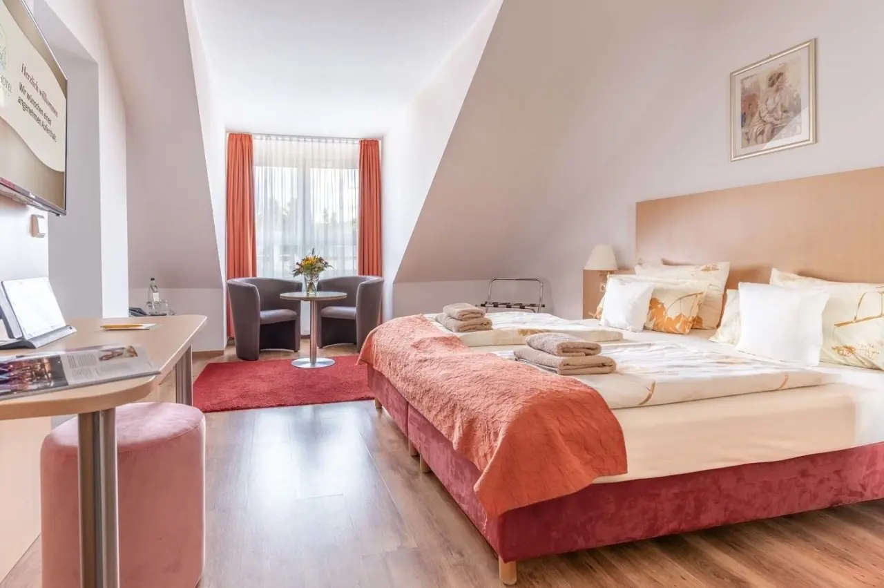 Gemütliches Doppelzimmer mit Dachschräge, Doppelbett und Sitzecke im Schlossberghotel Oberhof.