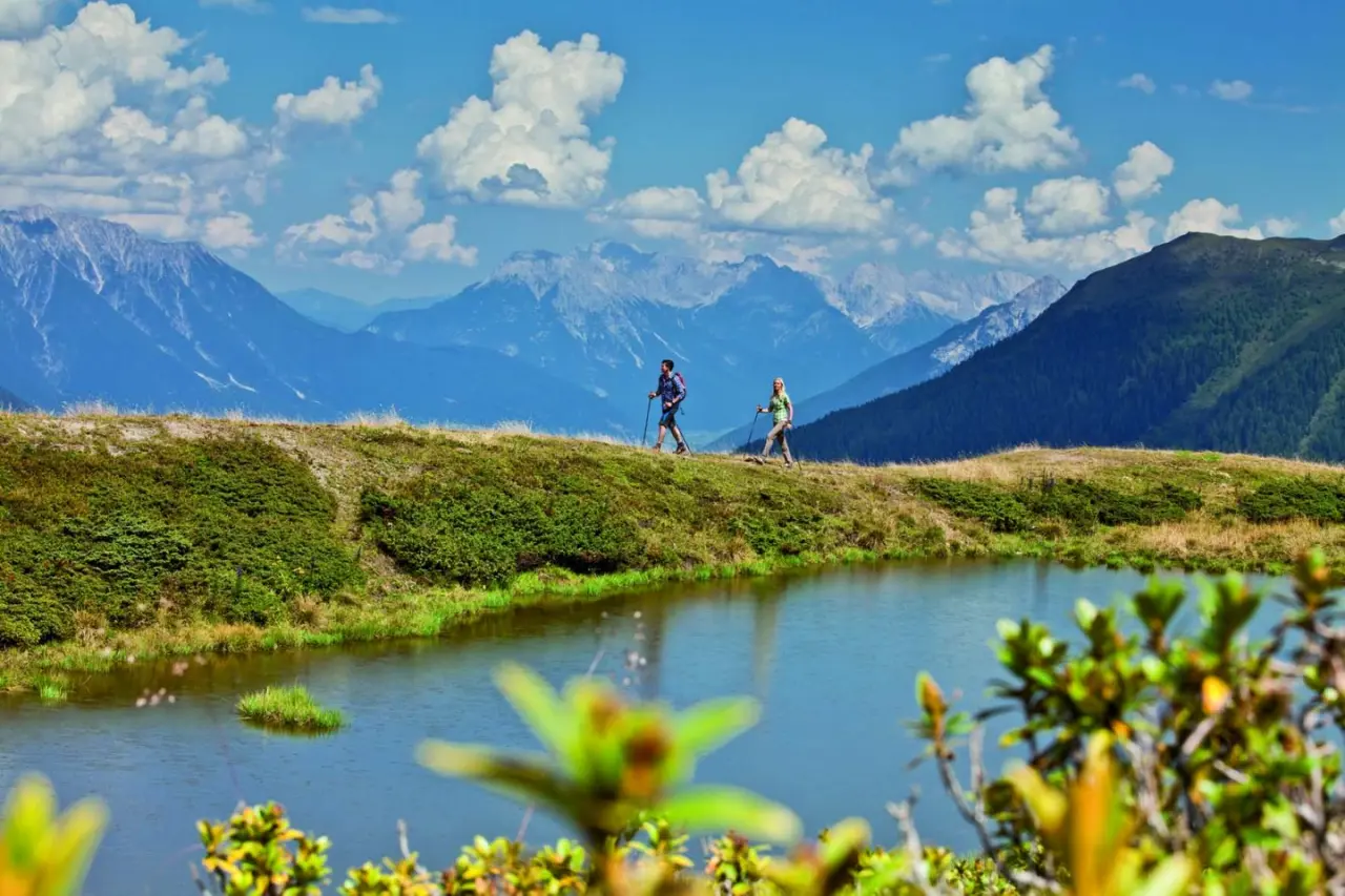 Zwei Wanderer am Bergsee mit Alpenpanorama in der Umgebung des Hotel Jägerhof, ideal für Aktivurlaub.