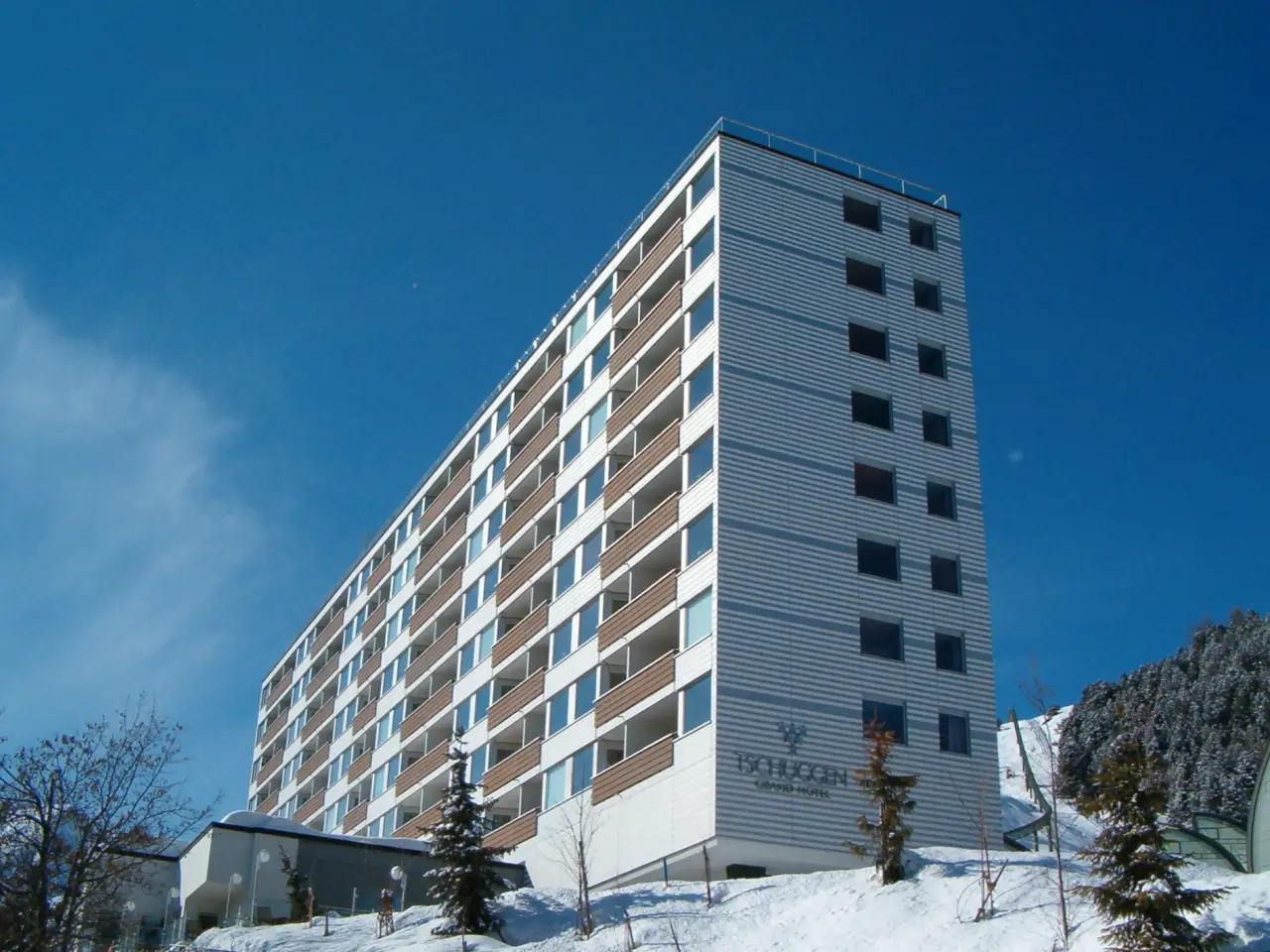 Moderne Aussenansicht des Tschuggen Grand Hotel in Arosa im Winter mit Schnee und blauem Himmel.