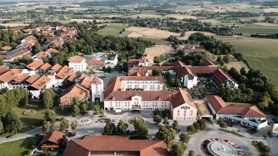 Luftaufnahme des weitläufigen Maximilian***** Quellness- und Golfhotels mit Poolbereich und umliegender Naturlandschaft.