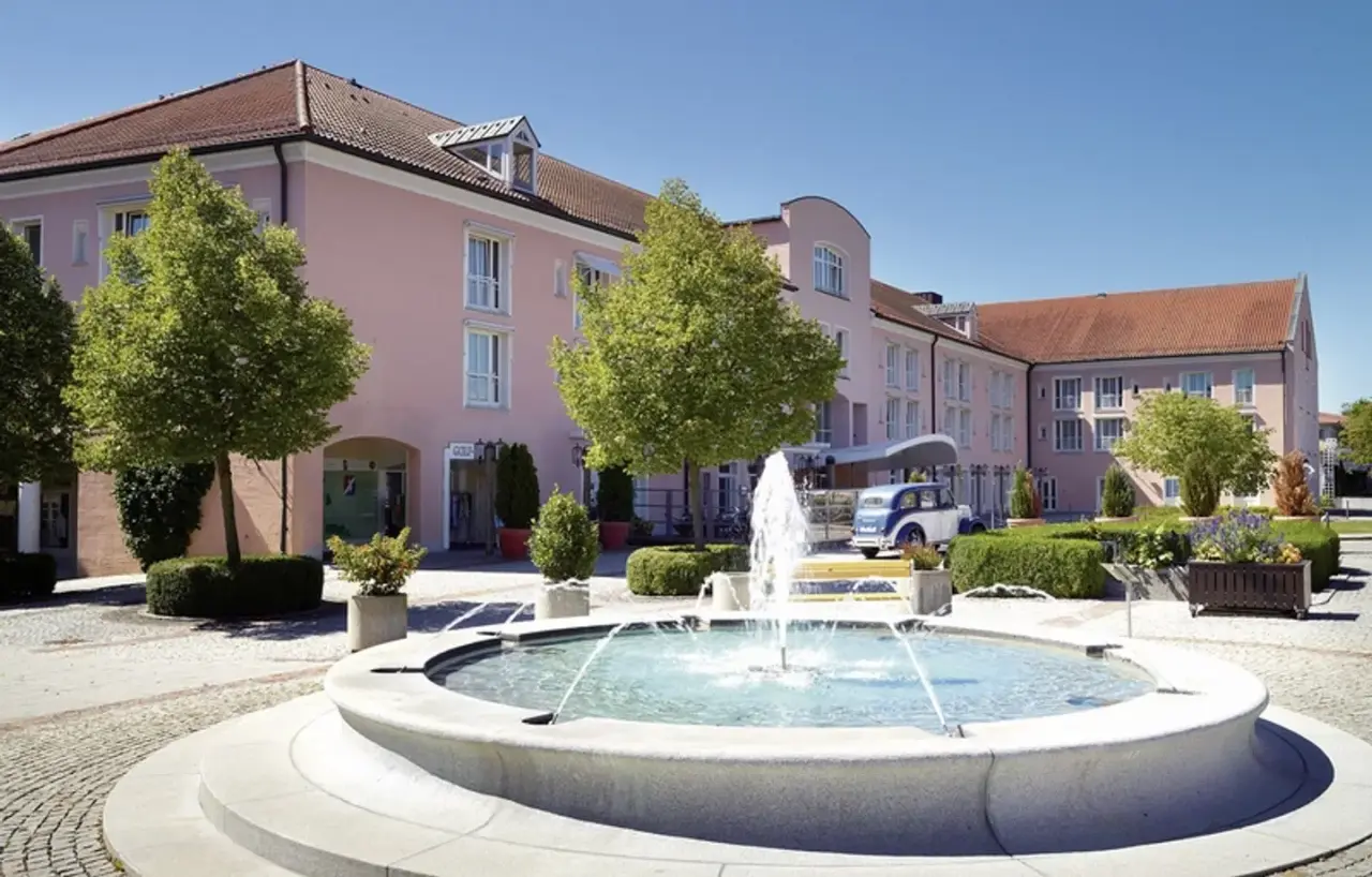 Aussenansicht des Maximilian***** Quellness- und Golfhotel mit Springbrunnen und historischem Auto.