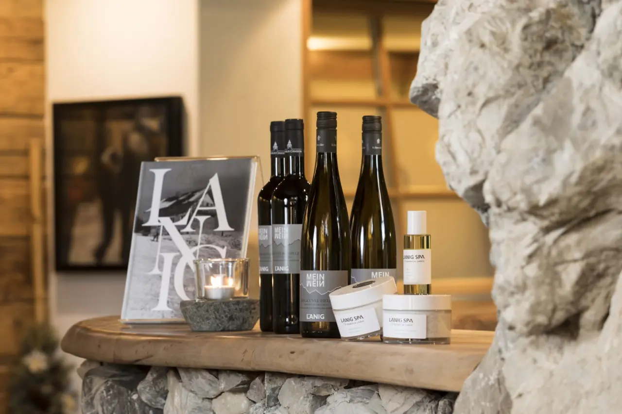 Exklusive Lanig Spa Pflegeprodukte und Weine auf einer rustikalen Holztheke im Hotel Lanig Resort & Spa.