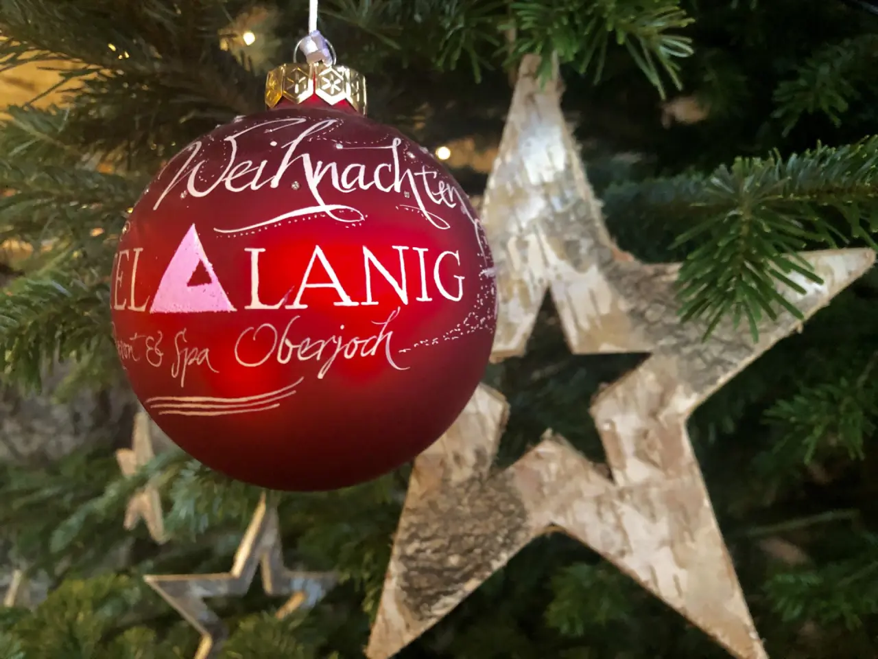 Rote Weihnachtskugel mit Aufschrift 'Weihnachten Hotel Lanig Resort & Spa Oberjoch' am Weihnachtsbaum.