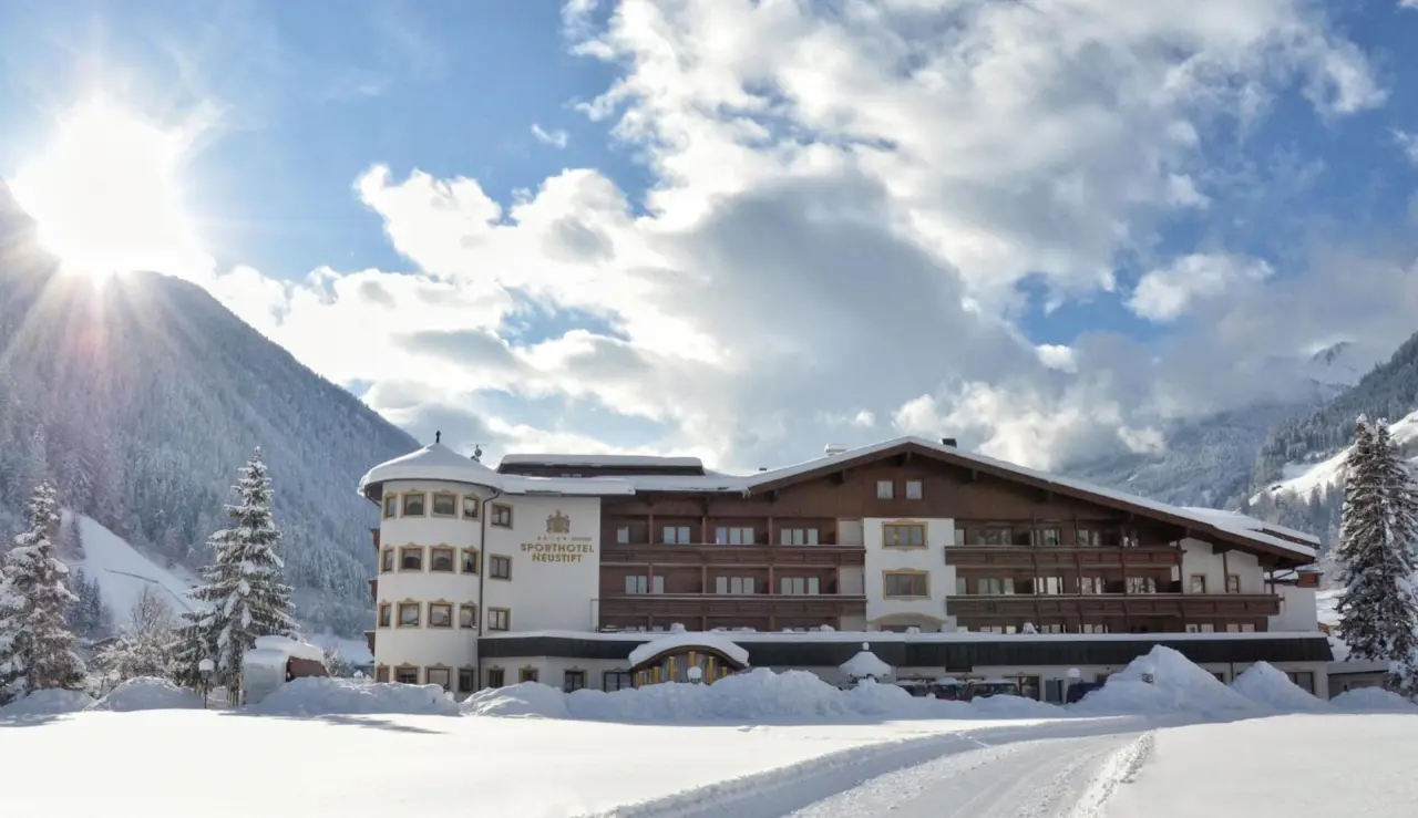 Sporthotel Neustift im Winter mit verschneiter Berglandschaft und strahlendem Sonnenschein.
