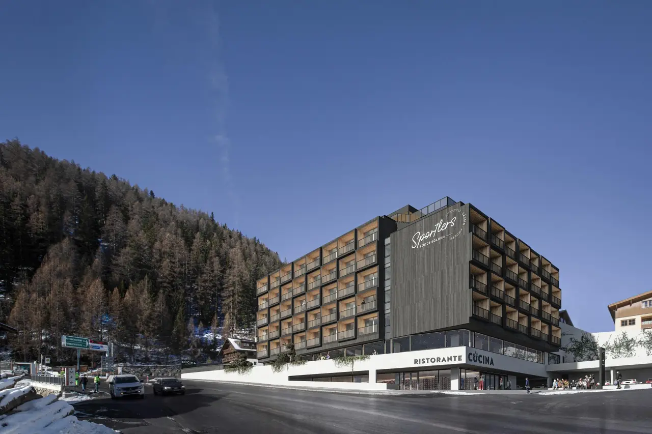 Modernes Hotel Sportlers Lodge Sölden mit Holzbalkonen und Restaurant im Winter vor bewaldeter Bergkulisse.