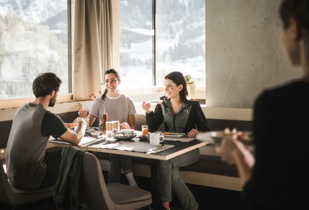 Gäste genießen ein reichhaltiges Frühstück mit Bergblick im Restaurant der Sportlers Lodge Sölden.