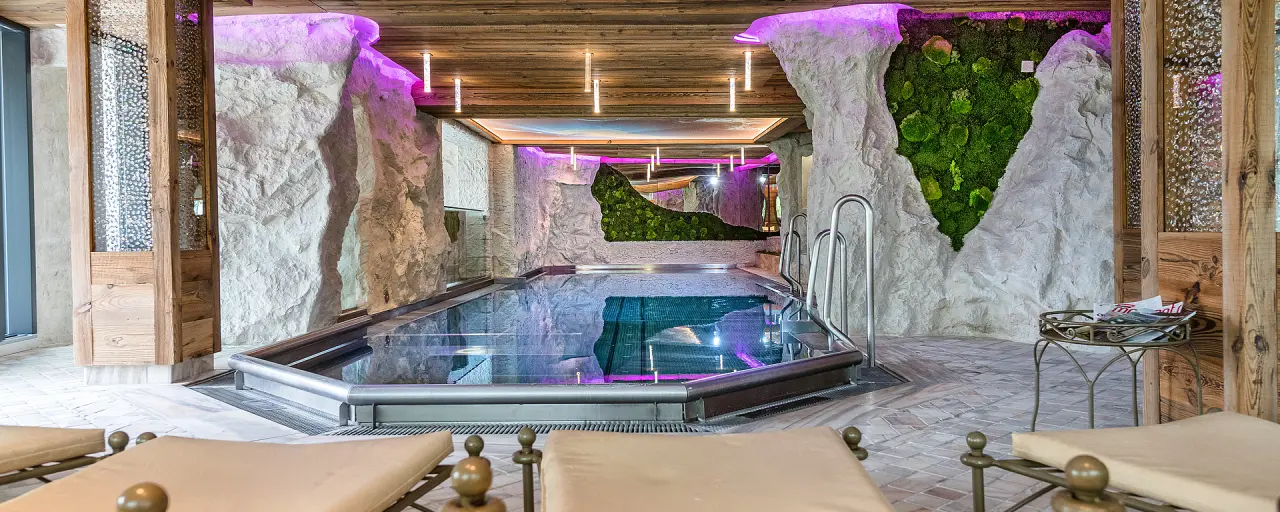 Beheizter Innenpool mit Fels- und Mooswand sowie lila Beleuchtung im Spa-Bereich des Hotel Winzer Wellness & Kuscheln.