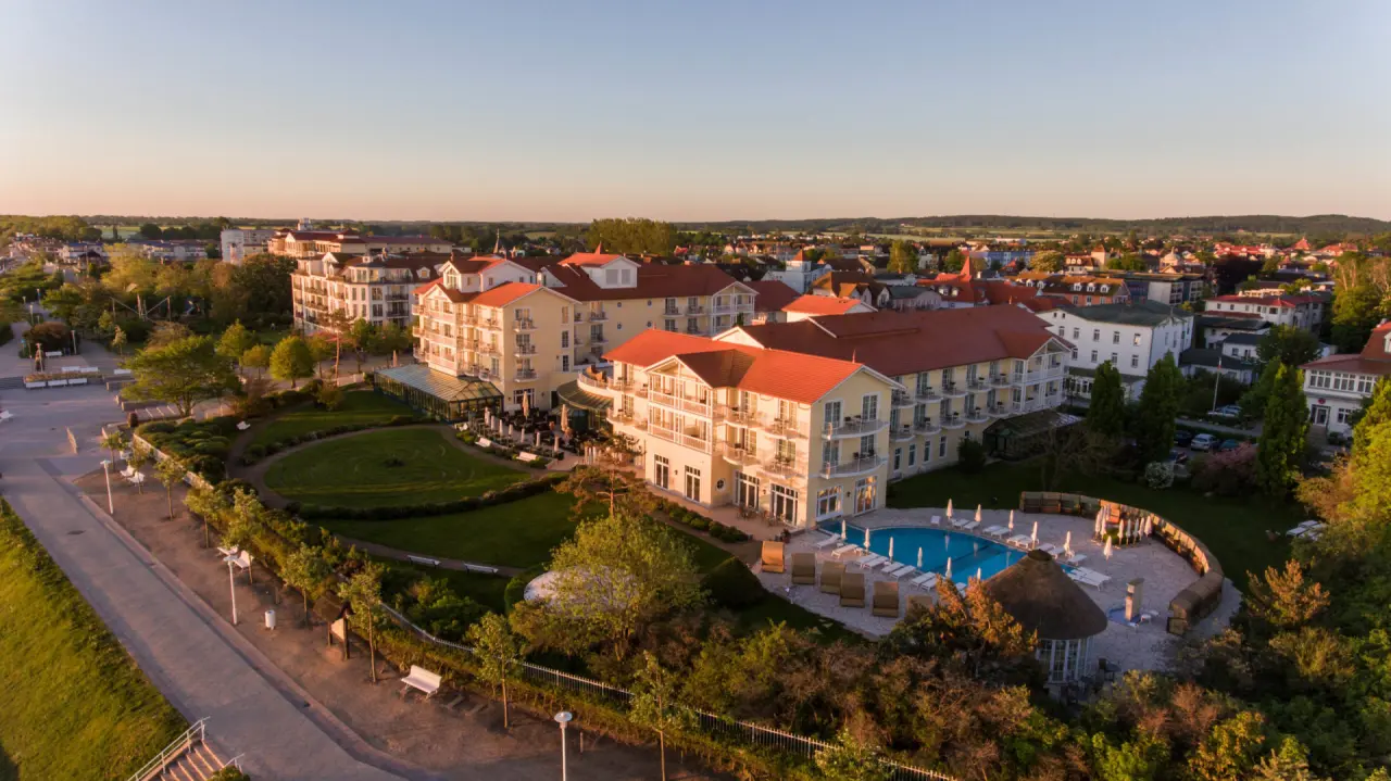 Luftaufnahme des Travel Charme Ostseehotel Kühlungsborn mit Aussenpool und Gartenanlage bei Sonnenuntergang.