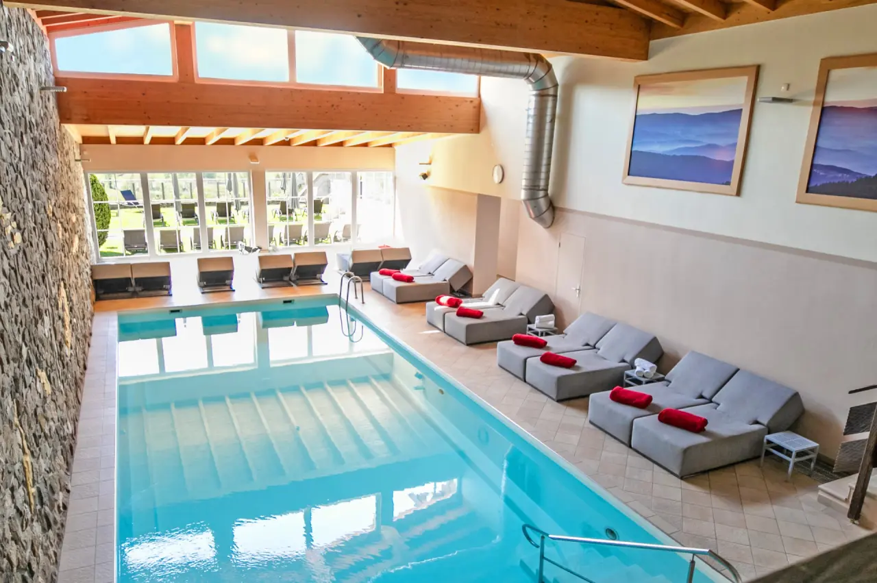 Innenpool mit bequemen Liegen und Steinwand im Wellnessbereich des Wellnesshotel Hofbräuhaus.