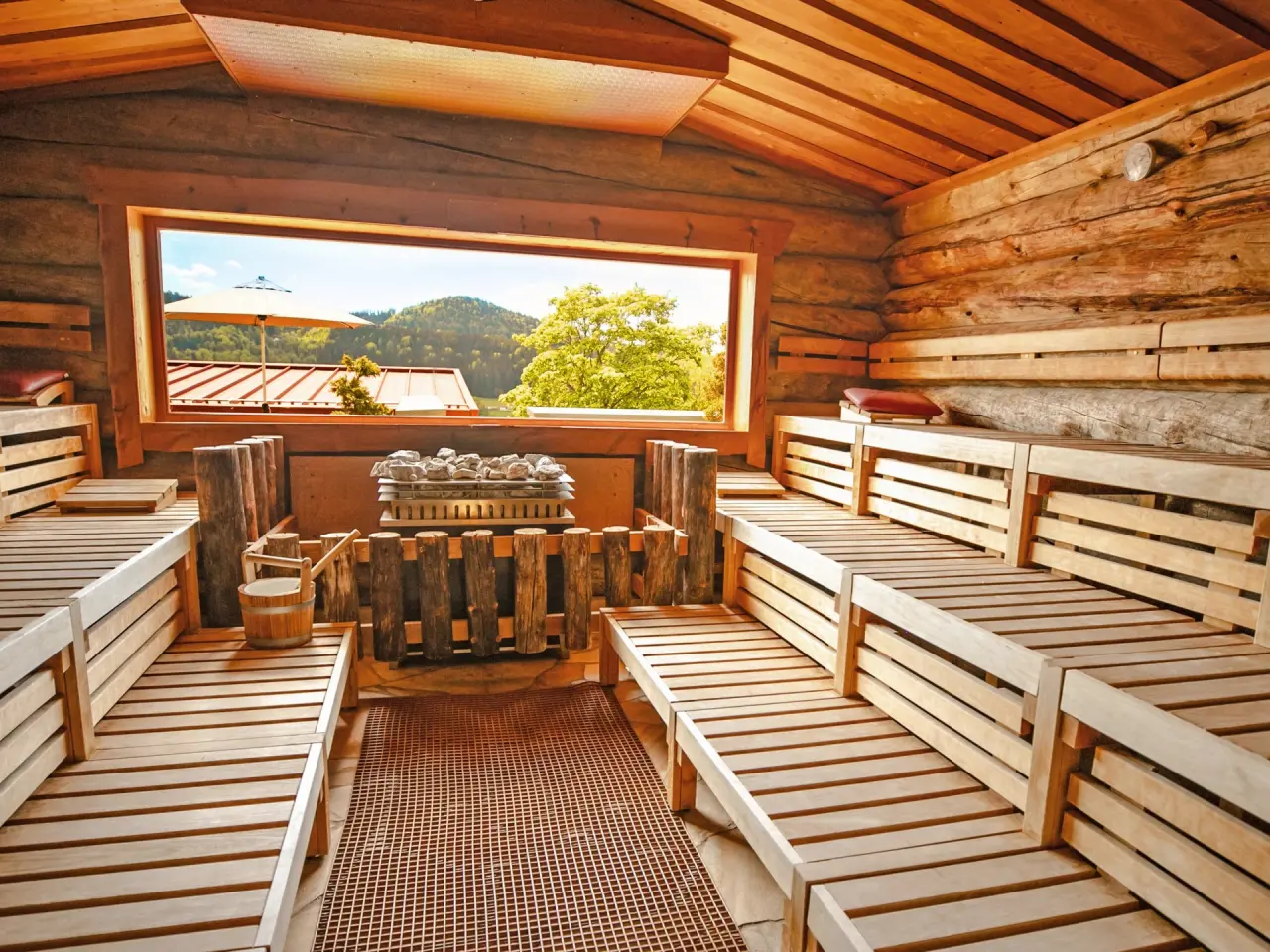 Helle Holzsauna im Wellnesshotel Hofbräuhaus mit Panoramablick auf die umliegende Natur und grüne Hügel. Perfekt zum Entspannen.