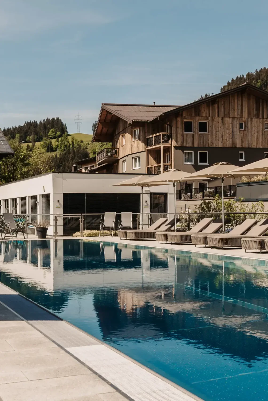 Hofgut Apartment & Lifestyle Resort Wagrain in Wagrain – Außenpool mit Sonnenliegen und Hotelgebäude | Wellnesshotel Salzburger Land