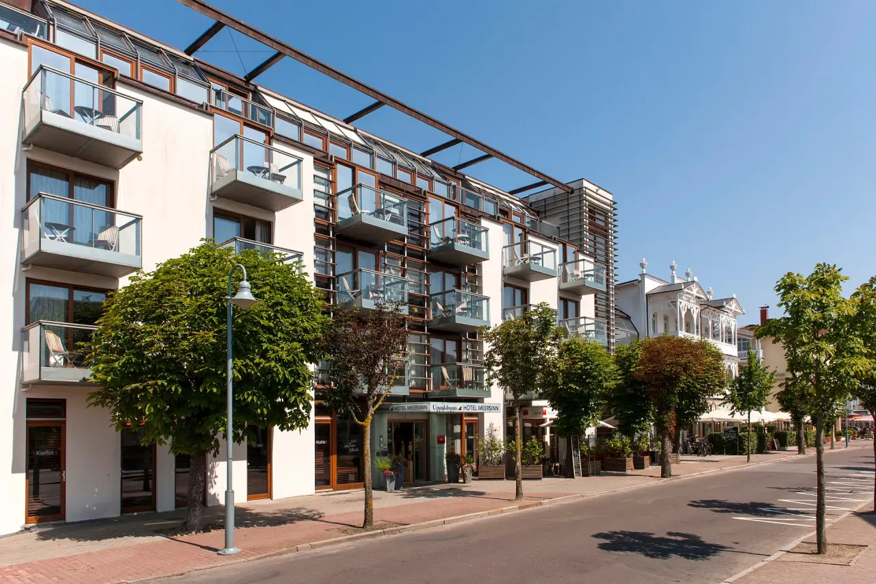 Moderne Aussenansicht des Hotel meerSinn Binz mit Balkonen und Bäumen an einem sonnigen Tag.