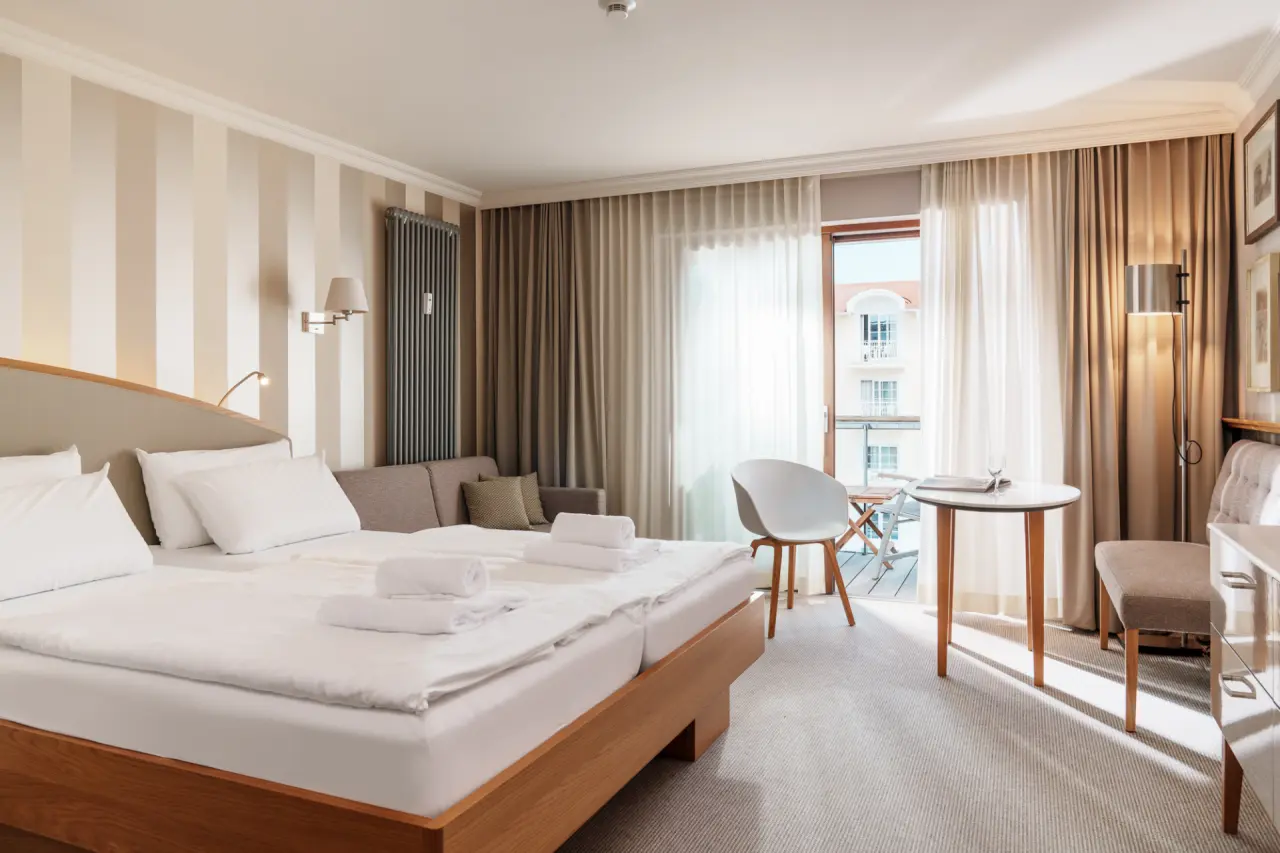 Helles, komfortables Hotelzimmer mit Doppelbett, Sofa und Balkon im Hotel meerSinn Binz, ideal zum Entspannen.
