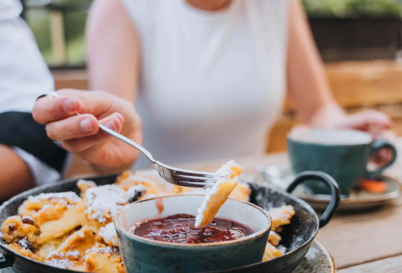 Gast genießt Kaiserschmarrn mit Fruchtsauce im Restaurant des Aparthotel Grünwald Resort Sölden.