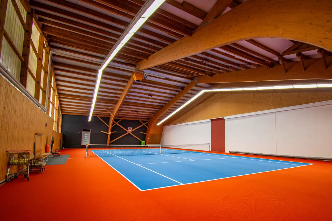 Indoor-Tennisplatz mit blauem Spielfeld und Holzdecke im Vital- und Wellnesshotel Albblick.