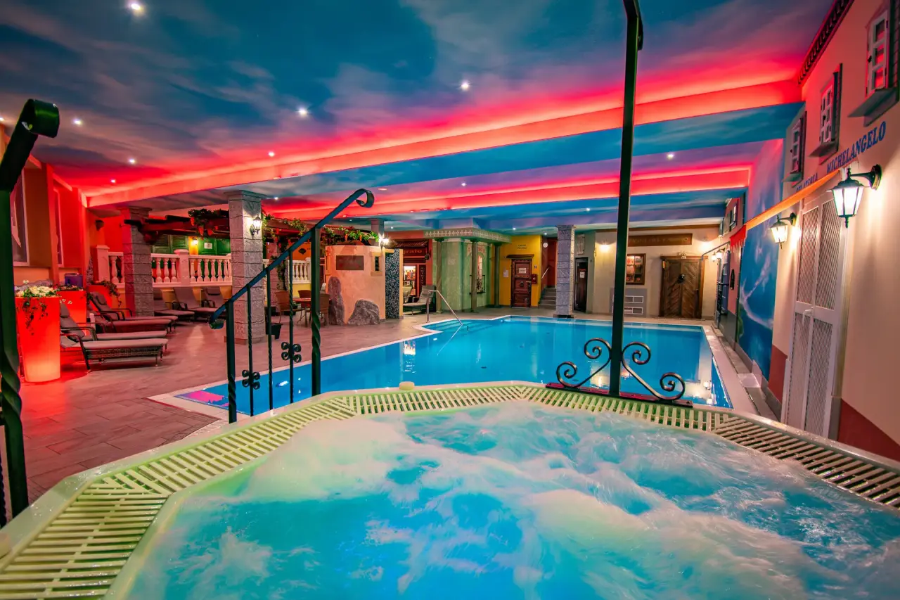 Großzügige Indoor-Poollandschaft mit sprudelndem Whirlpool und farbiger Beleuchtung im Vital- und Wellnesshotel Albblick.