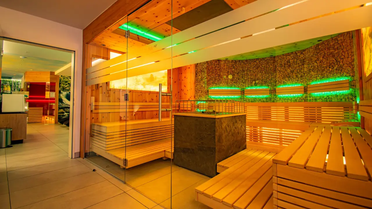 Moderne Finnische Sauna mit Holz und Steinwand sowie grüner LED-Beleuchtung im Vital- und Wellnesshotel Albblick.