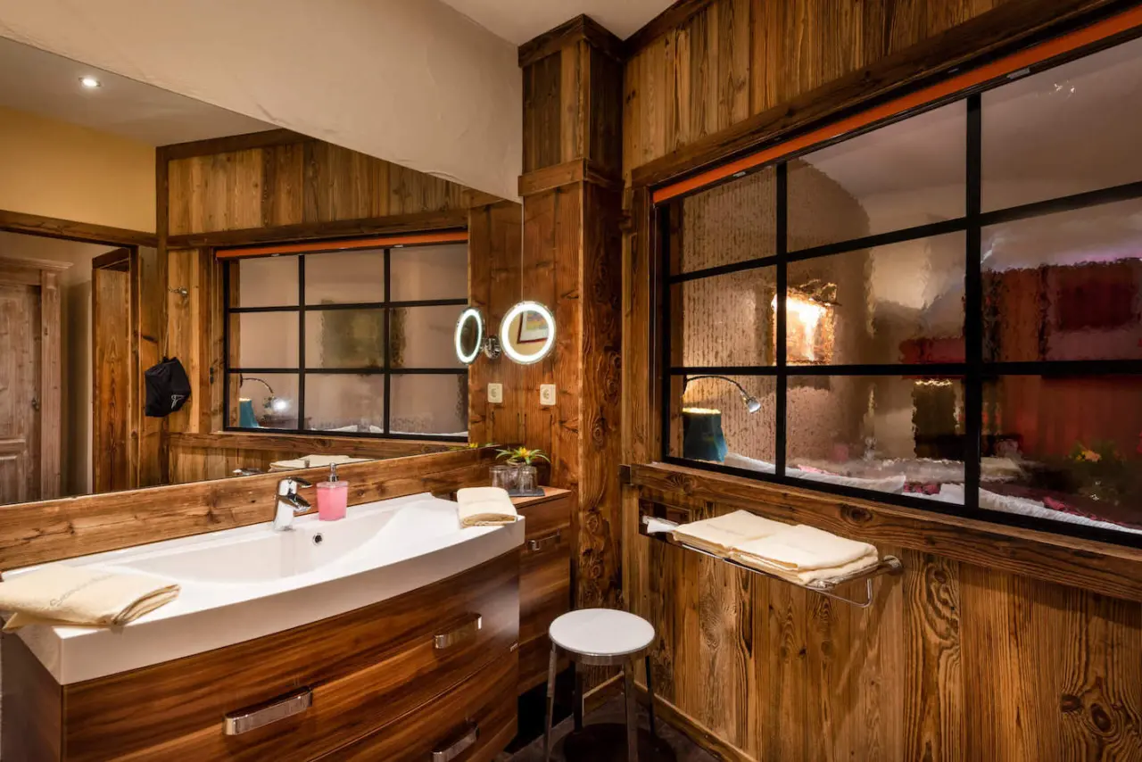 Modernes Badezimmer mit Holzvertäfelung, Waschtisch und großem Spiegel im Wellnesshotel Seeschlösschen.