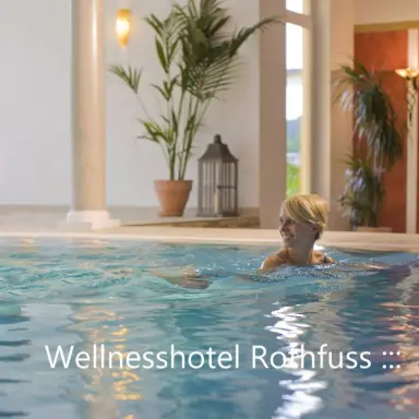 Lachende Frau im Innenpool des Wellnesshotel Rothfuss mit Pflanzen und Säulen im Hintergrund.