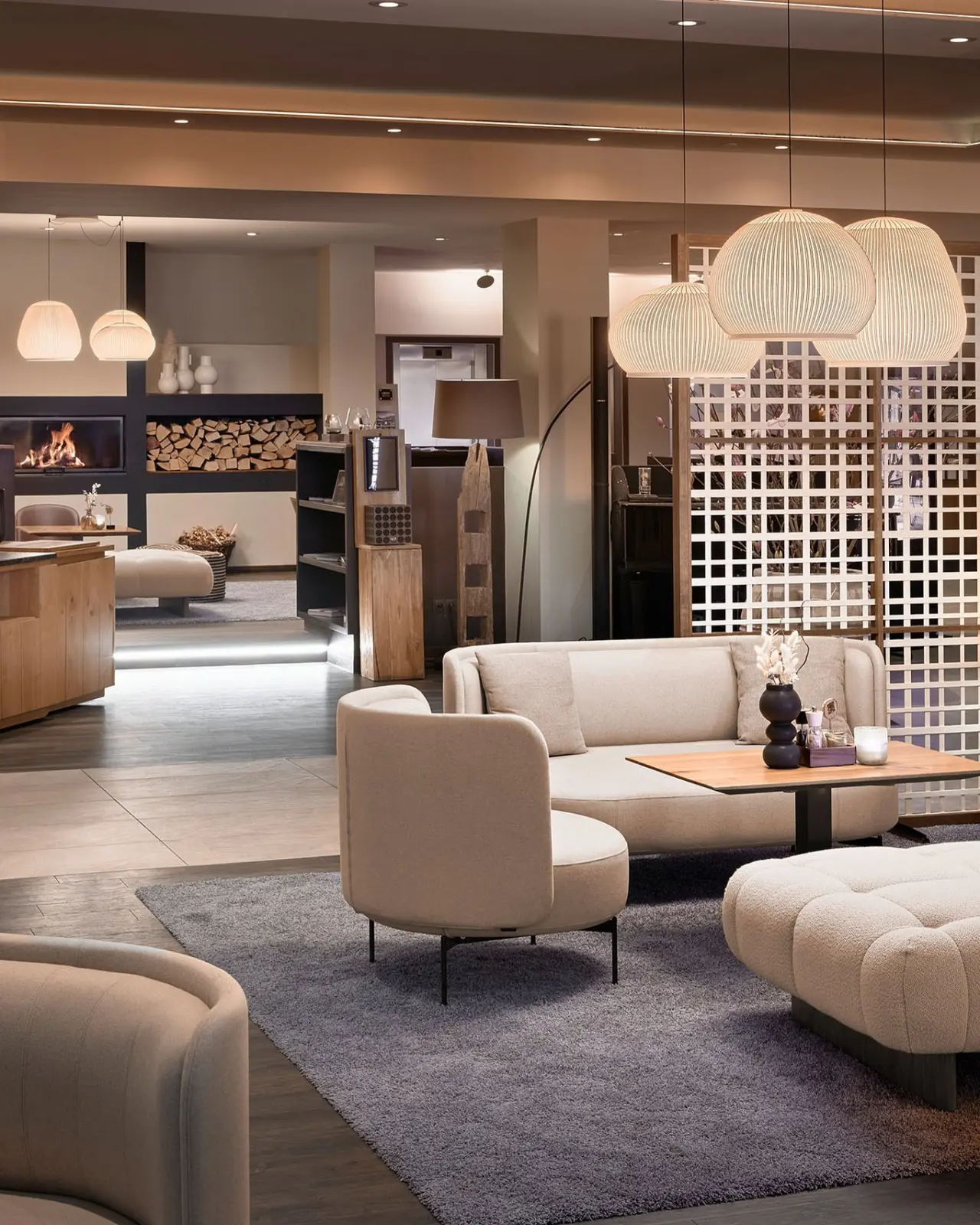 Moderne Hotellobby mit Kamin, bequemen Sitzgelegenheiten und stilvoller Beleuchtung im Panoramahotel Oberjoch.