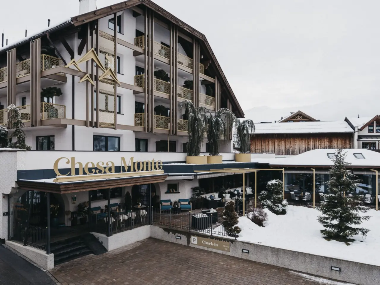 Aussenansicht des Hotel Chesa Monte****S im Winter mit Schnee und goldener Fassadenverzierung.