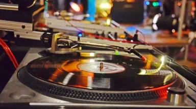 Nahaufnahme eines Plattenspielers mit Vinyl-Schallplatte und bunten Lichtern im Landhaus Stricker.