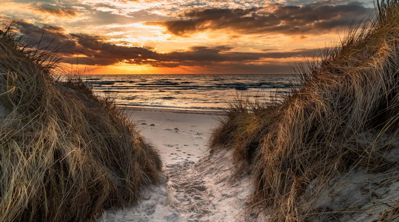 Sonnenuntergang über der Nordsee mit Dünenweg am Strand von Sylt, nahe dem Landhaus Stricker.