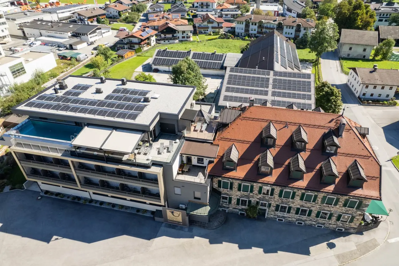 Luftaufnahme des Gasthof Hotel Post mit modernem Anbau, Rooftop-Pool und traditionellem Gebäude in ländlicher Umgebung.