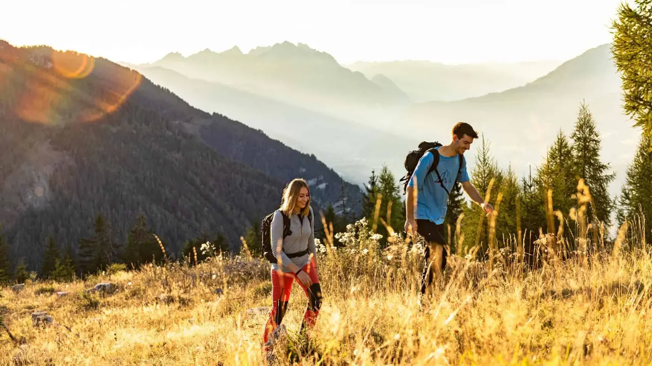 Zwei Wanderer mit Rucksäcken in goldener Abendsonne auf einem Bergpfad nahe dem Hotel Glocknerhof in den Alpen.