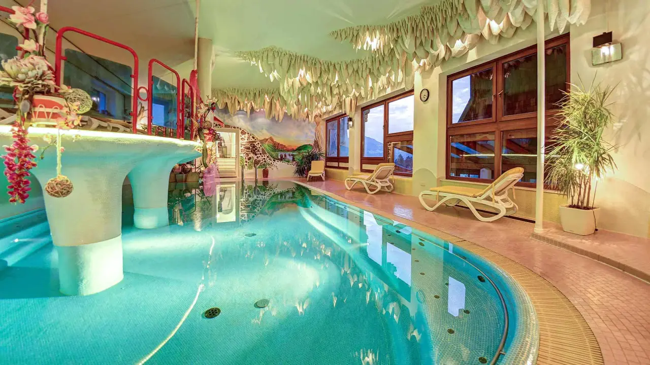 Innenpool mit Bergblick, Liegestühlen und Wandmalerei im Hotel Glocknerhof